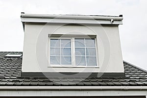 Stylish building with unfinished facade, white windows, modern black roof and dormer. Modern new farmhouse building exterior