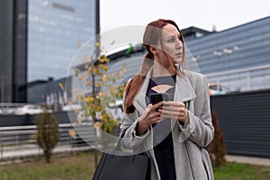 stylish business woman with a laptop in her hands on the background of an office building, concept of successful