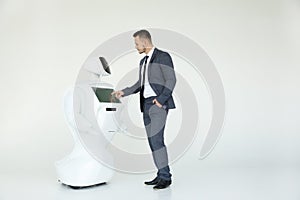 A stylish businessman communicates with a robot. Cybernetic system today. Modern Robotic Technologies. Humanoid