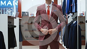 Stylish businessman man trying on a suit jacket in shop