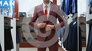 Stylish businessman man trying on a suit jacket in shop