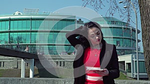 Stylish businesswoman in red dress using digital tablet outdoors
