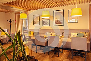 Stylish cafe interior. Sofa and comfortable chairs in restaurant. Indoor cafe furniture. Empty lounge zone with warm light lamps.