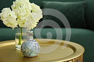 Stylish catalytic lamp with hydrangea on golden table in living room, space for text. Cozy interior