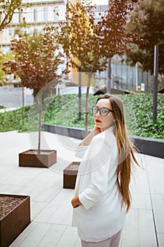 Stylish Caucasian business woman is standing near modern office building.