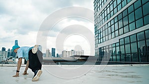 Stylish caucasian dancing man performing break dance at skyscraper. Endeavor.