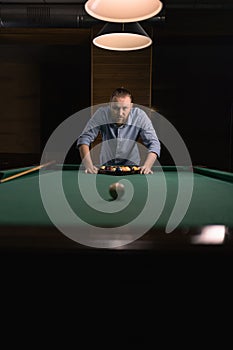 Stylish Caucasian man putting billiard balls in triangle rack on table prepare to game