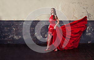 Stylish celebrity woman in red silky dress standing on vintage background