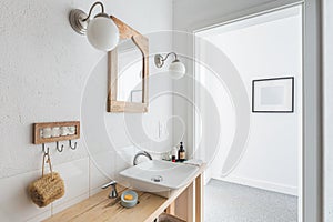 Ceramic sink on trendy wooden console table in small elegant bathroom
