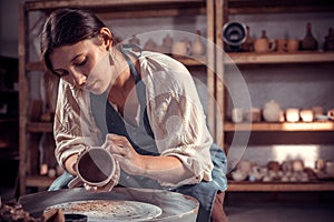Stylish ceramist master molding a vase of clay on a potter& x27;s wheel. Pottery workshop.