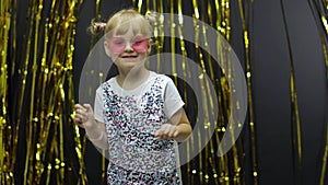 Stylish child dancing, make faces, waving hand in silly dance. Little blonde kid girl 4-5 years old