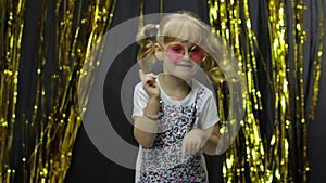 Stylish child dancing, make faces, waving hand in silly dance. Little blonde kid girl 4-5 years old