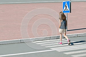 Stylish child in fashion clothes is walking along summer city crosswalk. Kid on pedestrian side walk. Concept pedestrians passing