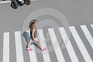 Stylish child in glasses, fashion clothes walking along summer city crosswalk. Kid on pedestrian side walk. Concept pedestrians