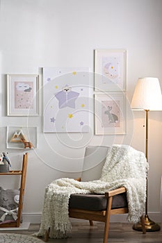 Stylish child`s room interior with armchair and beautiful pictures