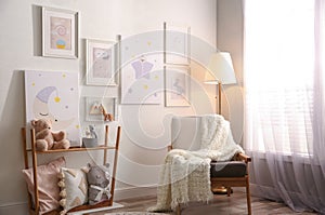Stylish child`s room interior with comfortable armchair and beautiful pictures