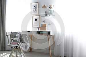 Stylish child`s room interior with desk and beautiful pictures