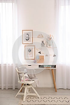 Stylish child`s room interior with desk and pictures