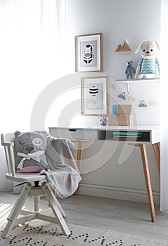 Stylish child`s room interior with desk and pictures