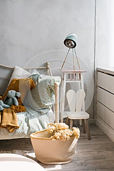 Stylish children`s room of the child. Wicker basket with flowers, pillows on the bed mint and brown