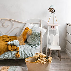 Stylish children`s room of the child. Wicker basket with flowers, pillows on the bed mint and brown