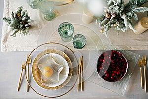 Stylish Christmas dinner setting. Gold and white plates, a star-shaped plate with tangerine. Berry pie on the table