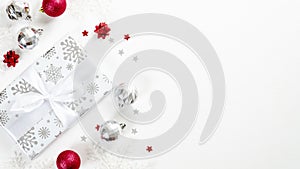 Stylish Christmas gift wit red and silver balls and decorations on white background. Flat lay, top view, copy space. Christmas