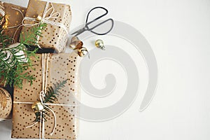 Stylish christmas gifts flat lay. Modern christmas gift boxes with fir branch, golden bell, festive paper and ornaments