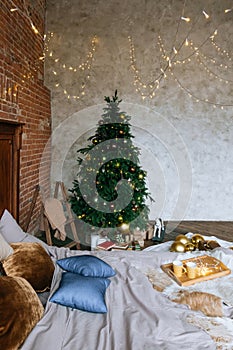 Stylish Christmas interior, bedroom with a lot of lights. Comfort home in a loft style with a decorated Christmas tree