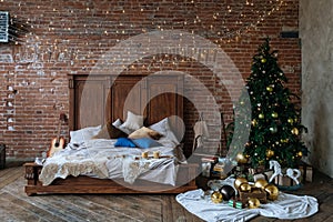 Stylish Christmas interior, bedroom with a lot of lights. Comfort home in a loft style with a decorated Christmas tree