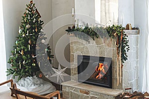 Stylish christmas living room with modern decorated christmas tree with vintage baubles and scandinavian decor on fireplace mantel