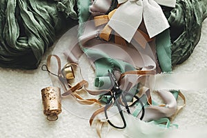 Stylish christmas vintage baubles, ribbons, brass bells and scissors on cozy white chair. Christmas ornaments aesthetics.