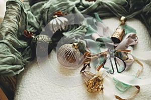 Stylish christmas vintage baubles, ribbons, brass bells and scissors on cozy white chair. Christmas ornaments aesthetics flat lay