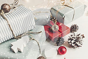 Stylish christmas wrapped presents with ornaments and cones on w