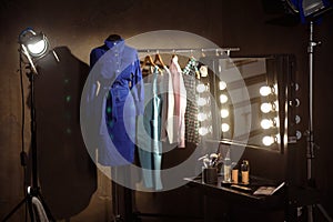 Stylish clothes and make-up products in dressing room