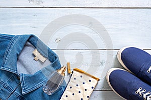 Stylish clothing look in flat lay style on blue pastel colored wooden desk