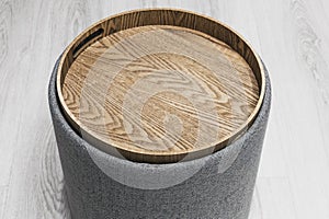 Stylish comfortable round padded stool with wooden top. cylindrical padded stool upholstered with gray fabric