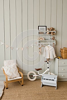 Stylish composition of a cozy Scandinavian interior of a children`s room with an armchair, plush and wooden toys, a rattan basket