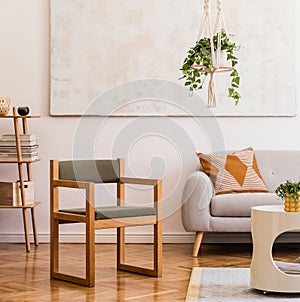 Stylish composition of creative spacious living room interior with grey sofa, chair, plants, carpet, paintings and accessories.