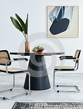 Stylish composition of dining room interior with design table, modern chairs, decoration, tropical leaf in vase, fruits.