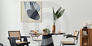 Stylish composition of dining room interior with design table, modern chairs, decoration, tropical leaf in vase, fruits.