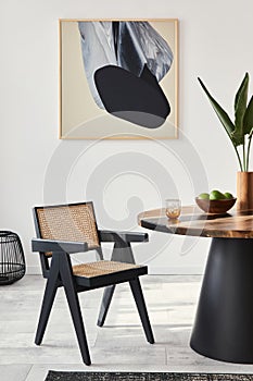 Stylish composition of dining room interior with design table, modern chairs, decoration, tropical leaf in vase, fruits, carpet.