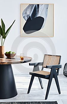 Stylish composition of dining room interior with design table, modern chairs, decoration, tropical leaf in vase, fruits, carpet.