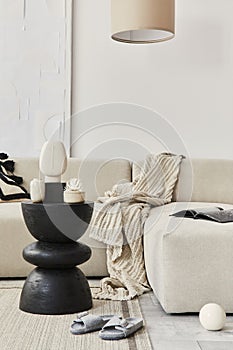 Stylish composition at fancy interior with sofa, lamp, wooden black coffee table, modern figure, blanket, pillow and book at home.