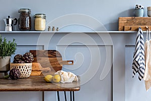 Stylish composition of kitchen interior with wooden family table, chairs, vegetables, herbs, plants, fruits, food supplies.