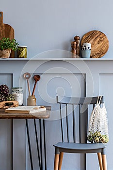 Stylish composition of kitchen interior with wooden family table, chairs, vegetables, herbs, plants, fruits, food supplies.