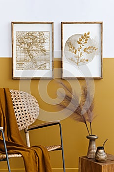 Stylish composition of living room interior with design rattan armchair, two mock up poster frames, plants, cube.