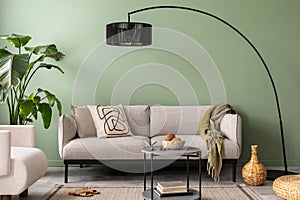 The stylish composition at living room interior with green wall, design gray sofa, coffee table, dark lamp and elegant personal