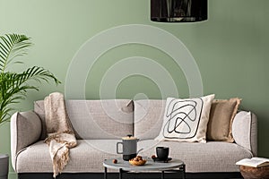 The stylish composition at living room interior with green wall, design gray sofa, coffee table, dark lamp and elegant personal
