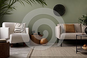 Stylish composition of living room interior with green wall, grey sofa with brown pillow. White armchair with patterned pilow,